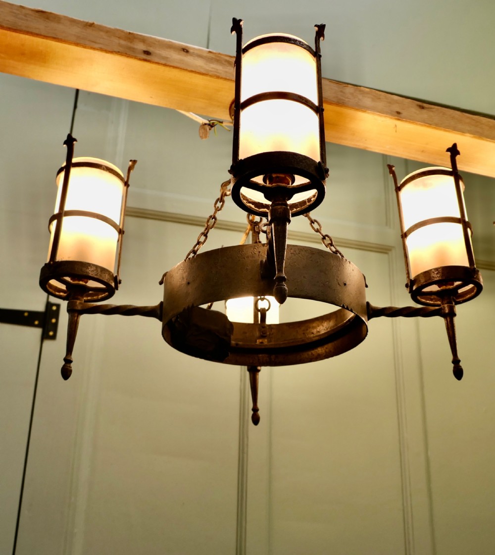 A pair of Arts and Crafts four-arm ceiling lights featuring twisted metal arms, cylindrical frosted shades, and chain suspensions. View V