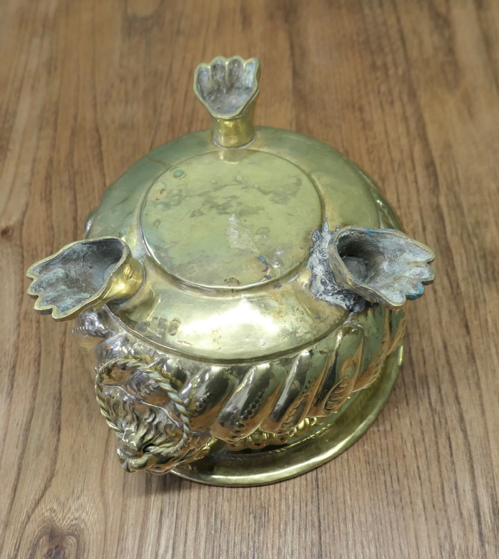 An ornate round brass jardiniere featuring gadrooned ribbed sides, lion mask ring handles, and paw feet. View V