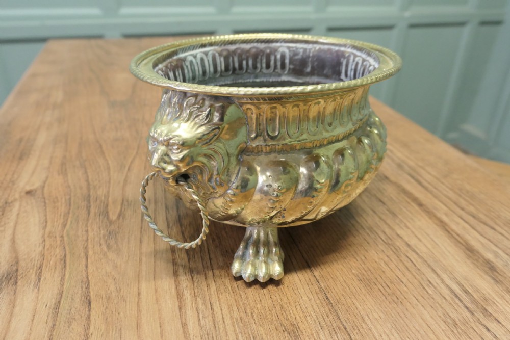 An ornate round brass jardiniere featuring gadrooned ribbed sides, lion mask ring handles, and paw feet. View VI
