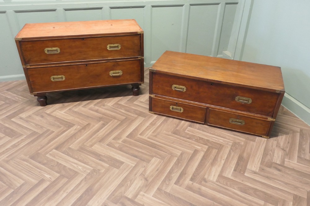 A two-section antique teak military campaign chest featuring brass corner straps, flush brass handles, turned feet, and a top secretaire drawer. View VII
