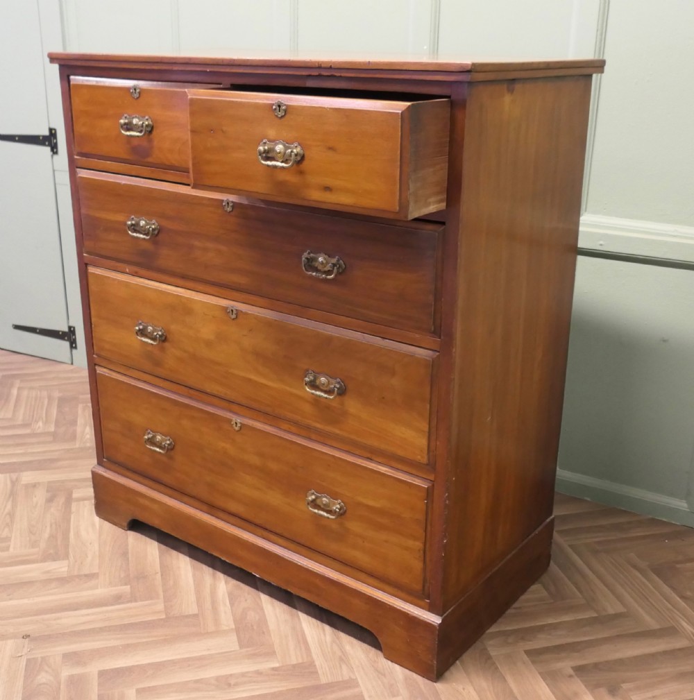 A large Edwardian walnut chest of drawers featuring two short drawers over three long drawers with brass drop handles. View II
