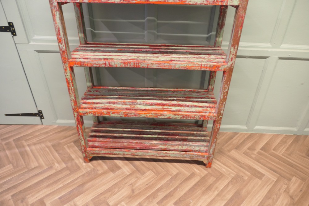 A tall freestanding French wooden shelving unit featuring five slatted shelves and a heavily distressed terracotta red and sage green painted finish. View III