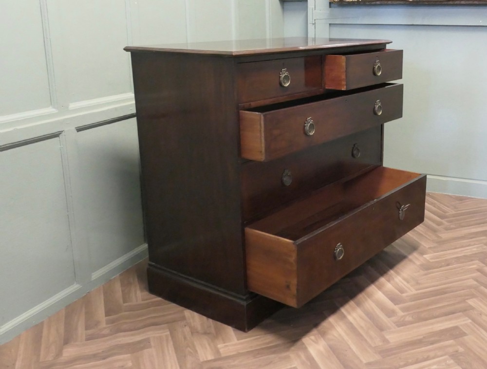 A 19th-century dark mahogany chest of drawers featuring a two-over-three drawer configuration with circular brass ring handles and a solid plinth base. View V