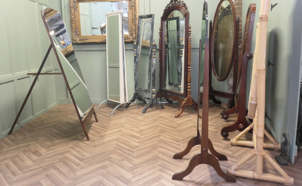 A tall Art Deco full-length cheval dressing mirror with clipped upper corners set within a dark timber frame supported by an easel stand. View VI