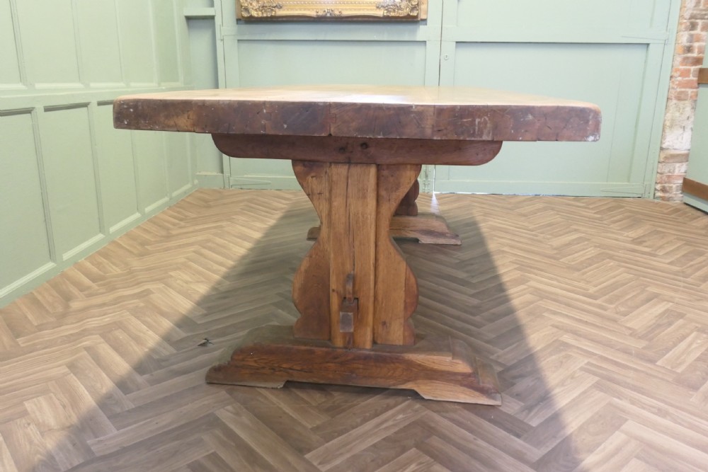 A large French oak monastery dining table featuring a thick rectangular plank top supported by heavy trestle end legs and a pegged stretcher. View V