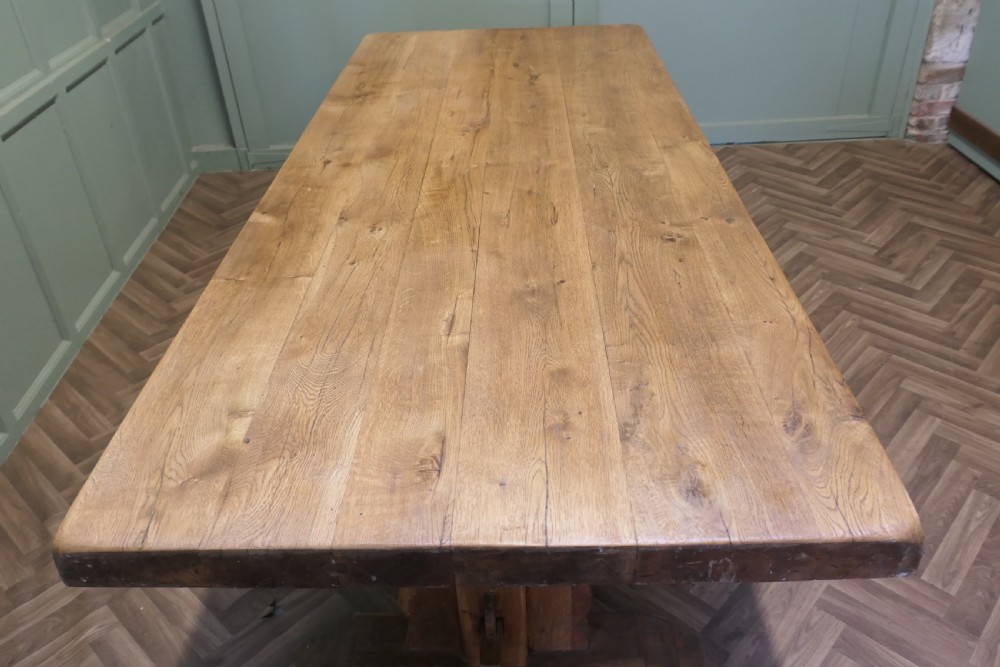 A large French oak monastery dining table featuring a thick rectangular plank top supported by heavy trestle end legs and a pegged stretcher. View VI
