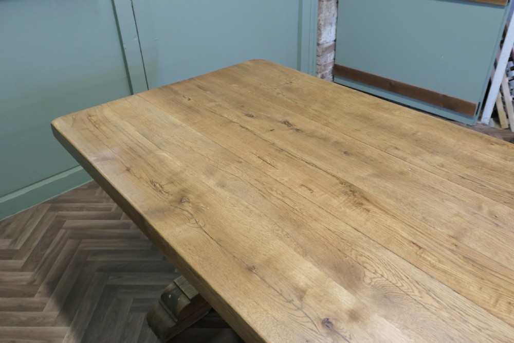 A large French oak monastery dining table featuring a thick rectangular plank top supported by heavy trestle end legs and a pegged stretcher. View VII