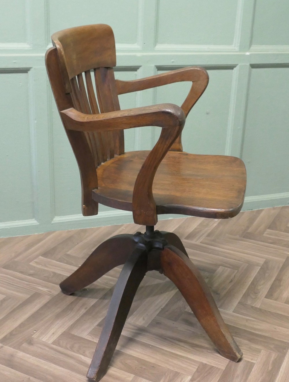 A wooden Art Deco swivel desk chair featuring curved armrests, a slatted backrest, and a splayed four-legged base. View VI