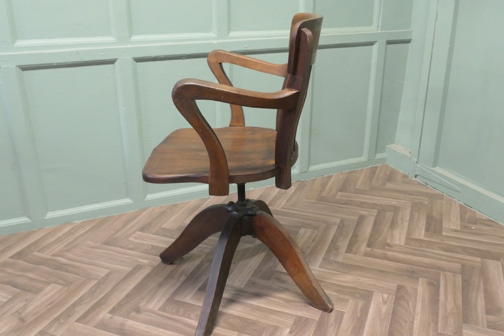 A wooden Art Deco swivel desk chair featuring curved armrests, a slatted backrest, and a splayed four-legged base. View VII