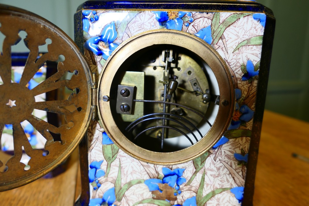 A three-piece French porcelain clock garniture set featuring a central rectangular mantel clock flanked by two matching side vases decorated with blue floral patterns and cobalt blue gilded borders. View III