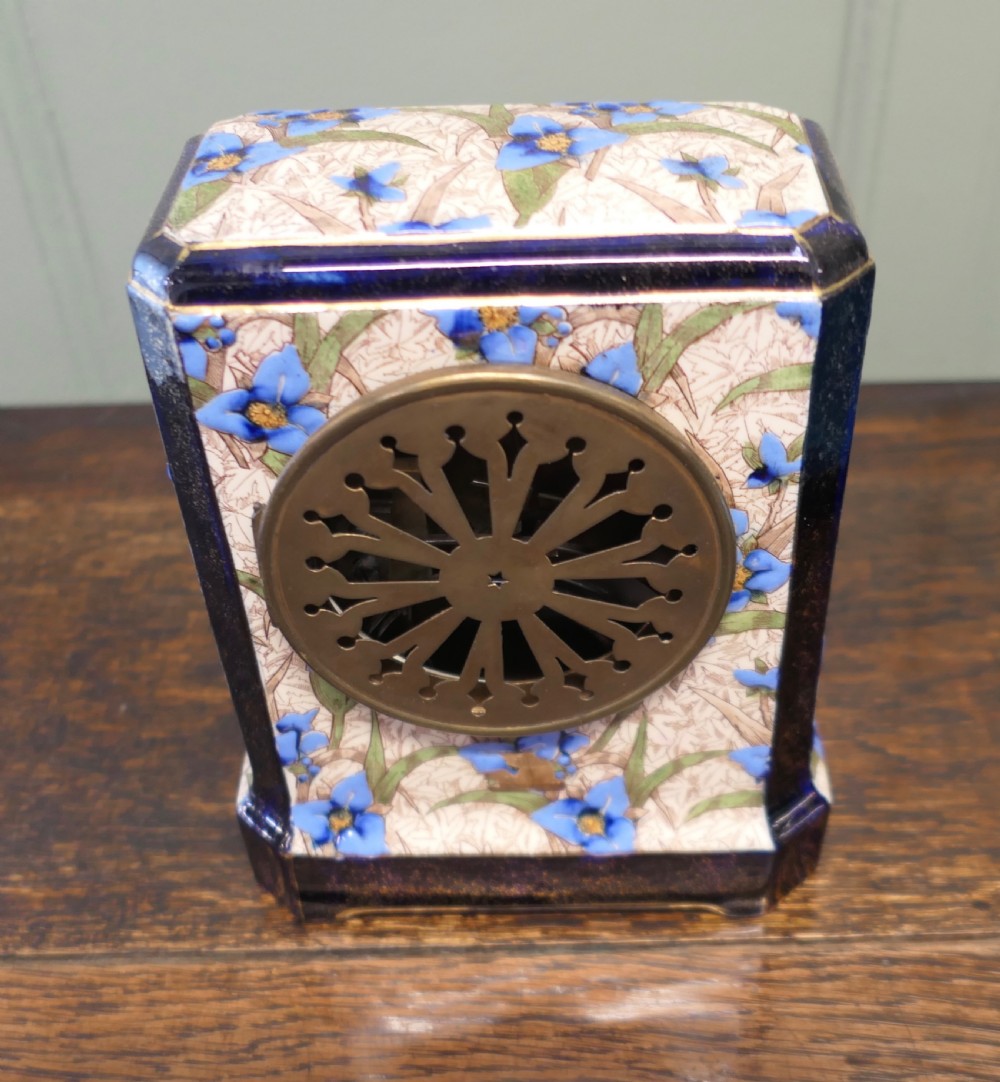 A three-piece French porcelain clock garniture set featuring a central rectangular mantel clock flanked by two matching side vases decorated with blue floral patterns and cobalt blue gilded borders. View V