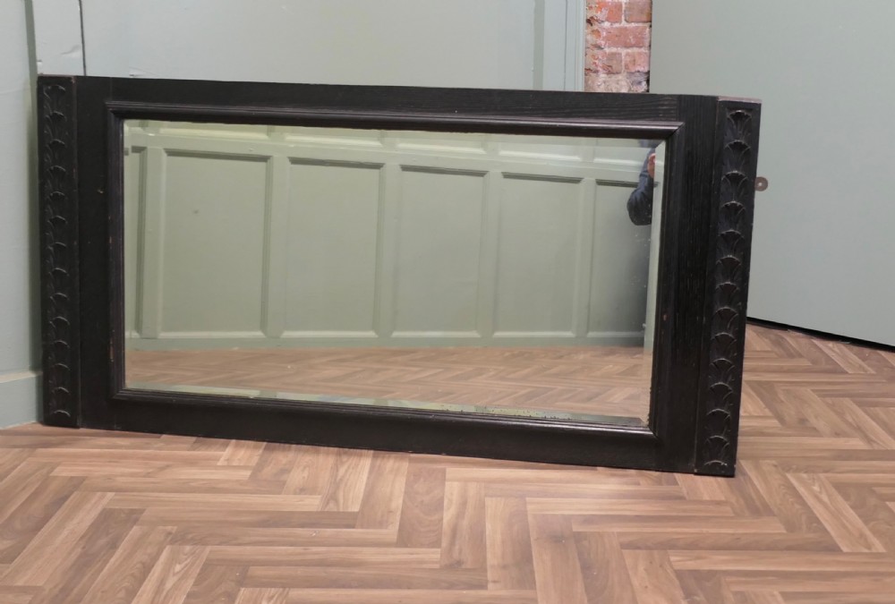 A large nineteenth-century rectangular mirror featuring a dark stained oak frame with carved foliate borders along the vertical sides.