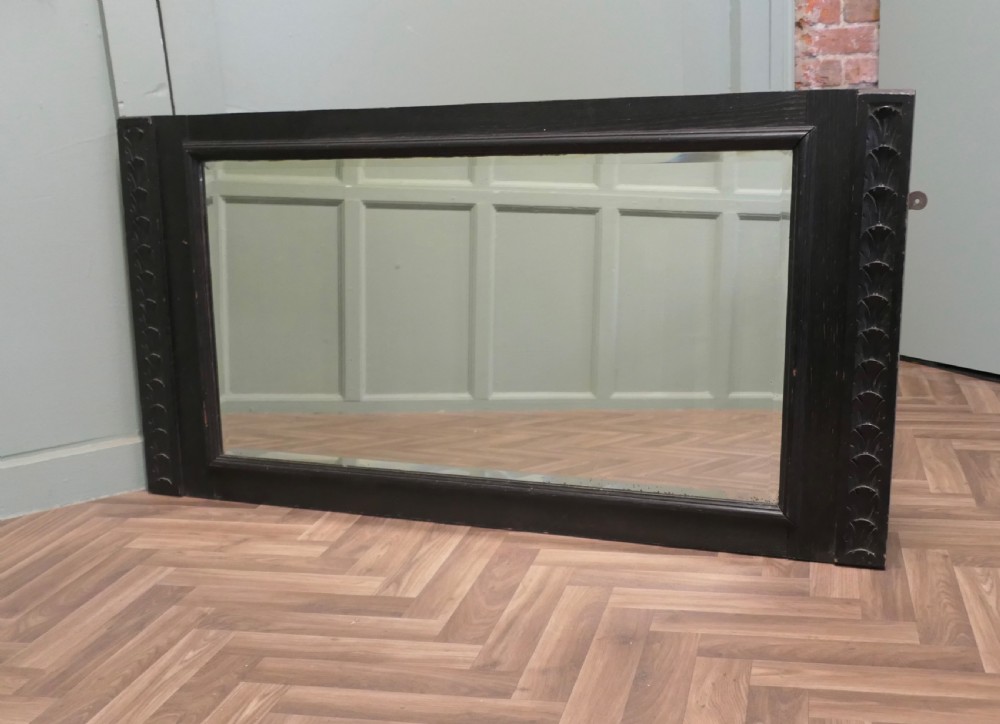 A large nineteenth-century rectangular mirror featuring a dark stained oak frame with carved foliate borders along the vertical sides. View IV
