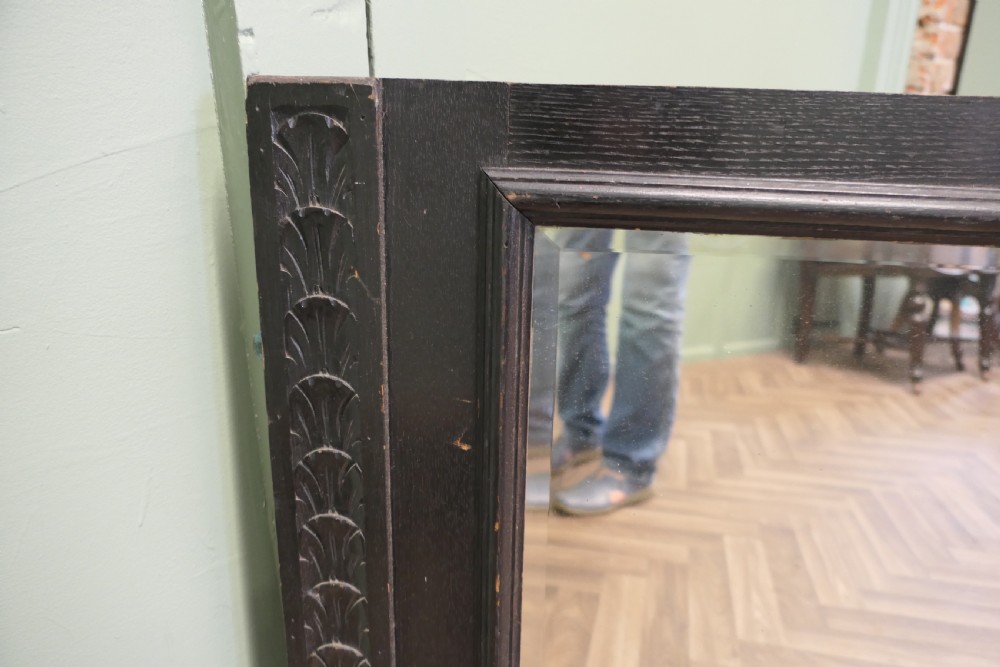 A large nineteenth-century rectangular mirror featuring a dark stained oak frame with carved foliate borders along the vertical sides. View VI