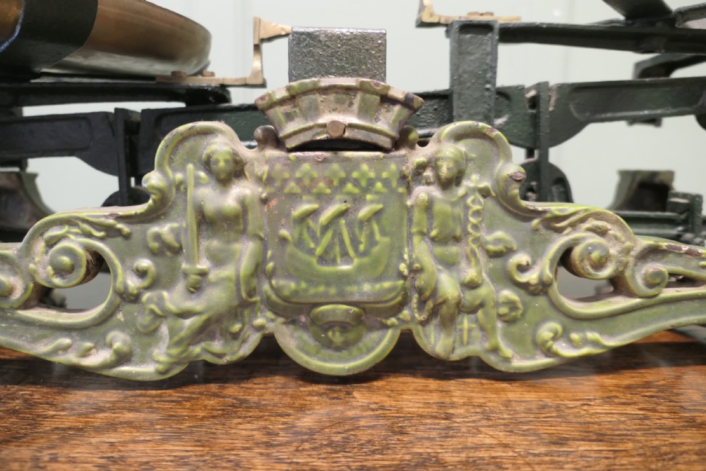 A nineteenth-century French grocers balance scale featuring a green patinated cast iron frame with ornate heraldic relief and double brass pans. View III