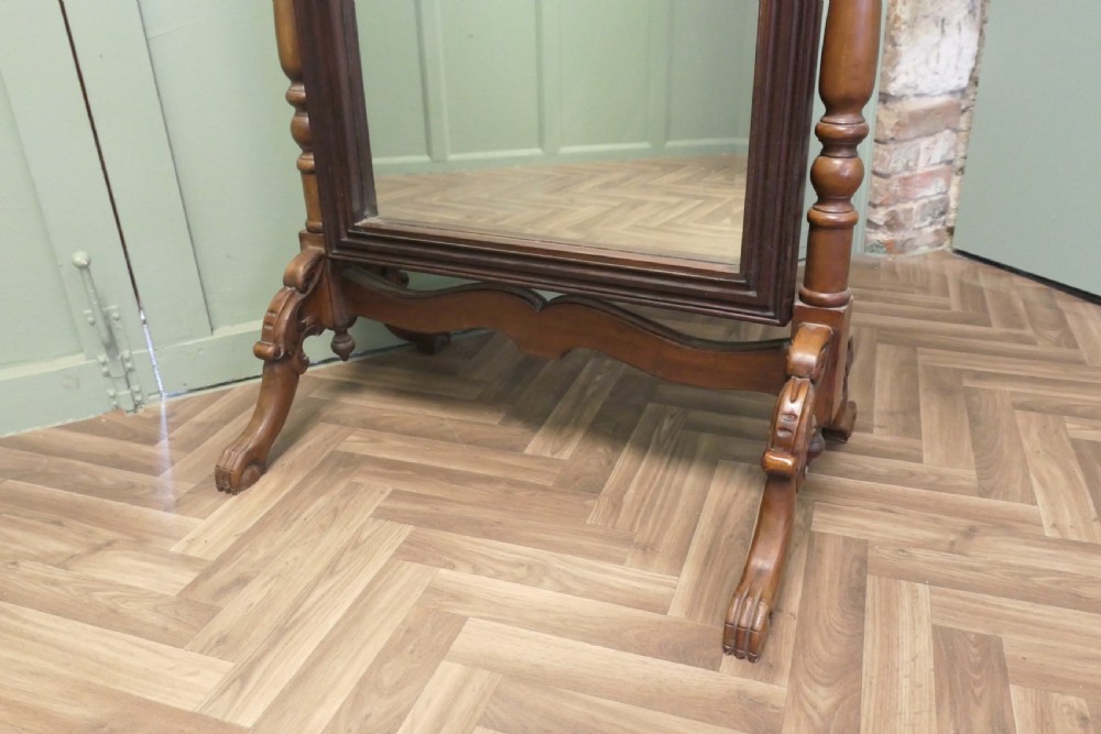 A Victorian carved mahogany cheval dressing mirror with an arched cresting top frame and turned side columns on splayed legs. View IV