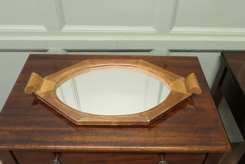 An octagonal wooden Art Deco mirror tray featuring carved scroll side handles and a central glass insert.
