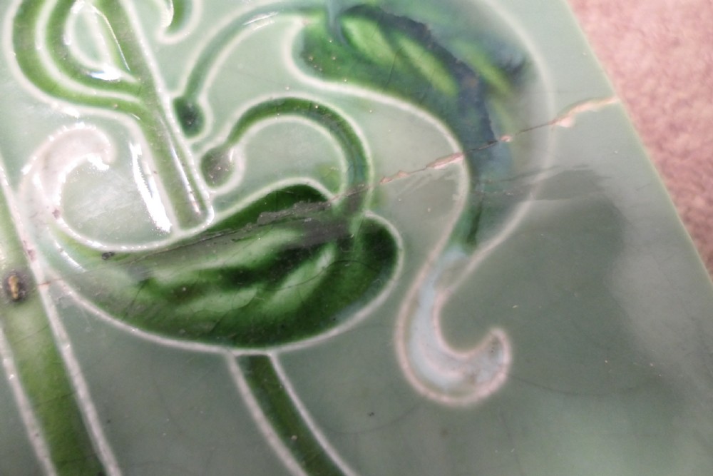 A set of eight rectangular green glazed ceramic tiles featuring embossed Art Nouveau stylised yellow and white floral motifs with curving green stems. View VI