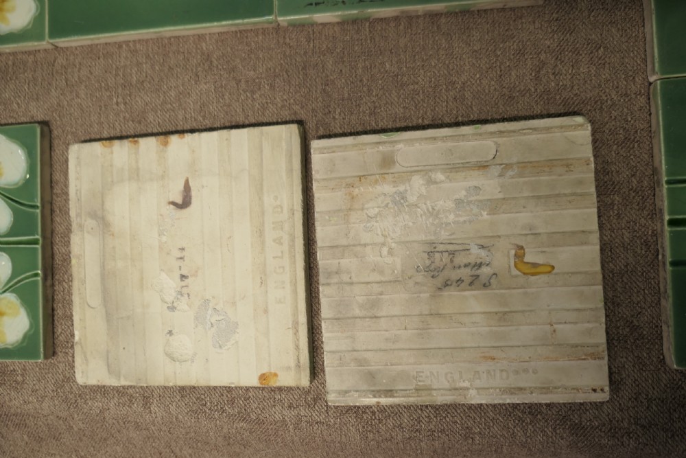 A set of eight rectangular green glazed ceramic tiles featuring embossed Art Nouveau stylised yellow and white floral motifs with curving green stems. View VII