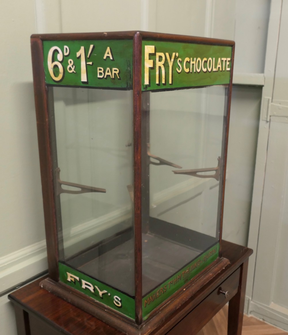An Edwardian mahogany and glass countertop display cabinet featuring green advertising panels with gold Frys Chocolate lettering.