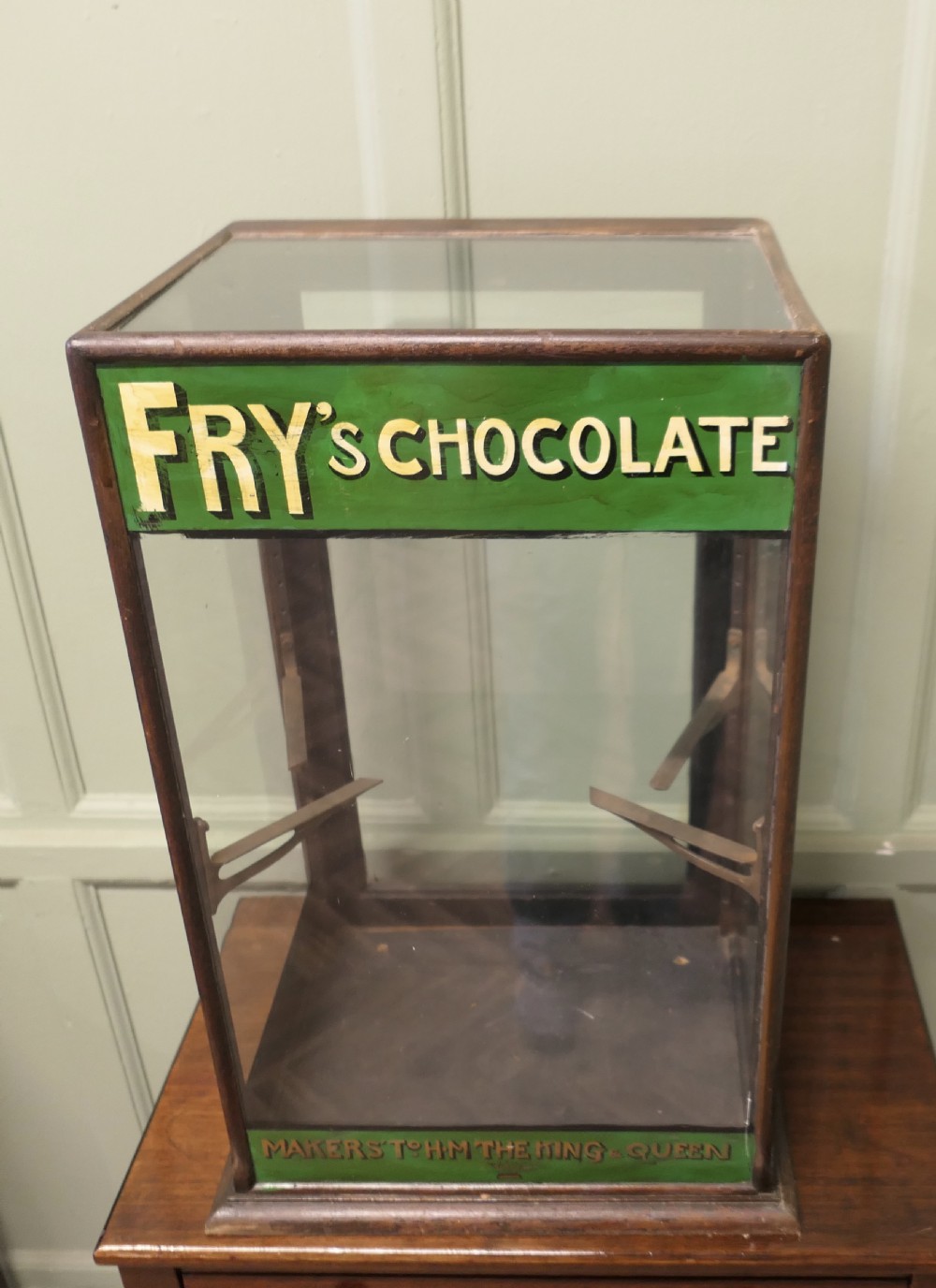 An Edwardian mahogany and glass countertop display cabinet featuring green advertising panels with gold Frys Chocolate lettering. View IV