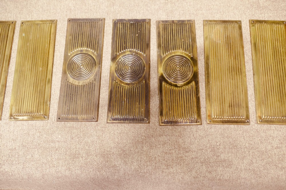 A set of twelve rectangular Art Deco brass door finger plates featuring linear reeded decoration and central concentric circle motifs. View II