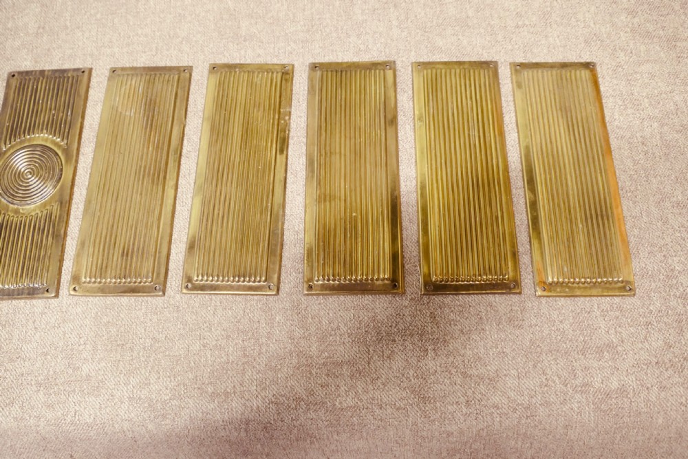 A set of twelve rectangular Art Deco brass door finger plates featuring linear reeded decoration and central concentric circle motifs. View III