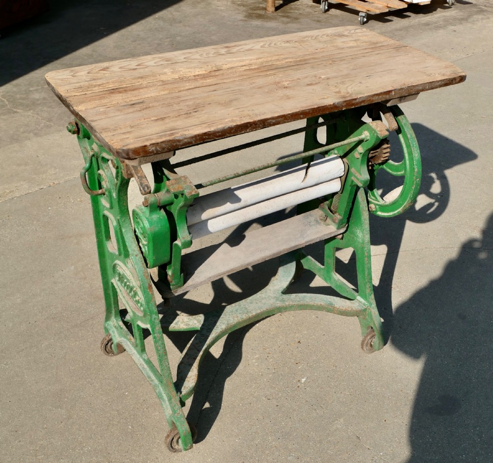 A green painted cast-iron mangle featuring an embossed Fulda logo, iron wheels, tension screws, and a hinged wooden pine top. View II