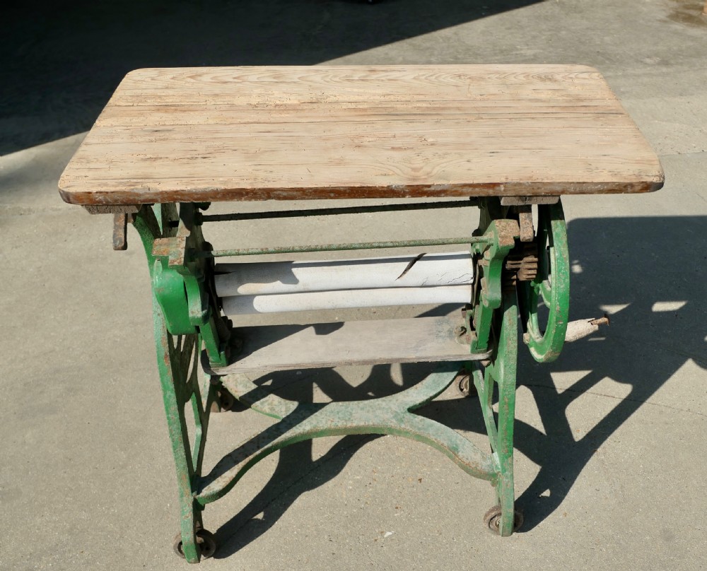 A green painted cast-iron mangle featuring an embossed Fulda logo, iron wheels, tension screws, and a hinged wooden pine top. View V