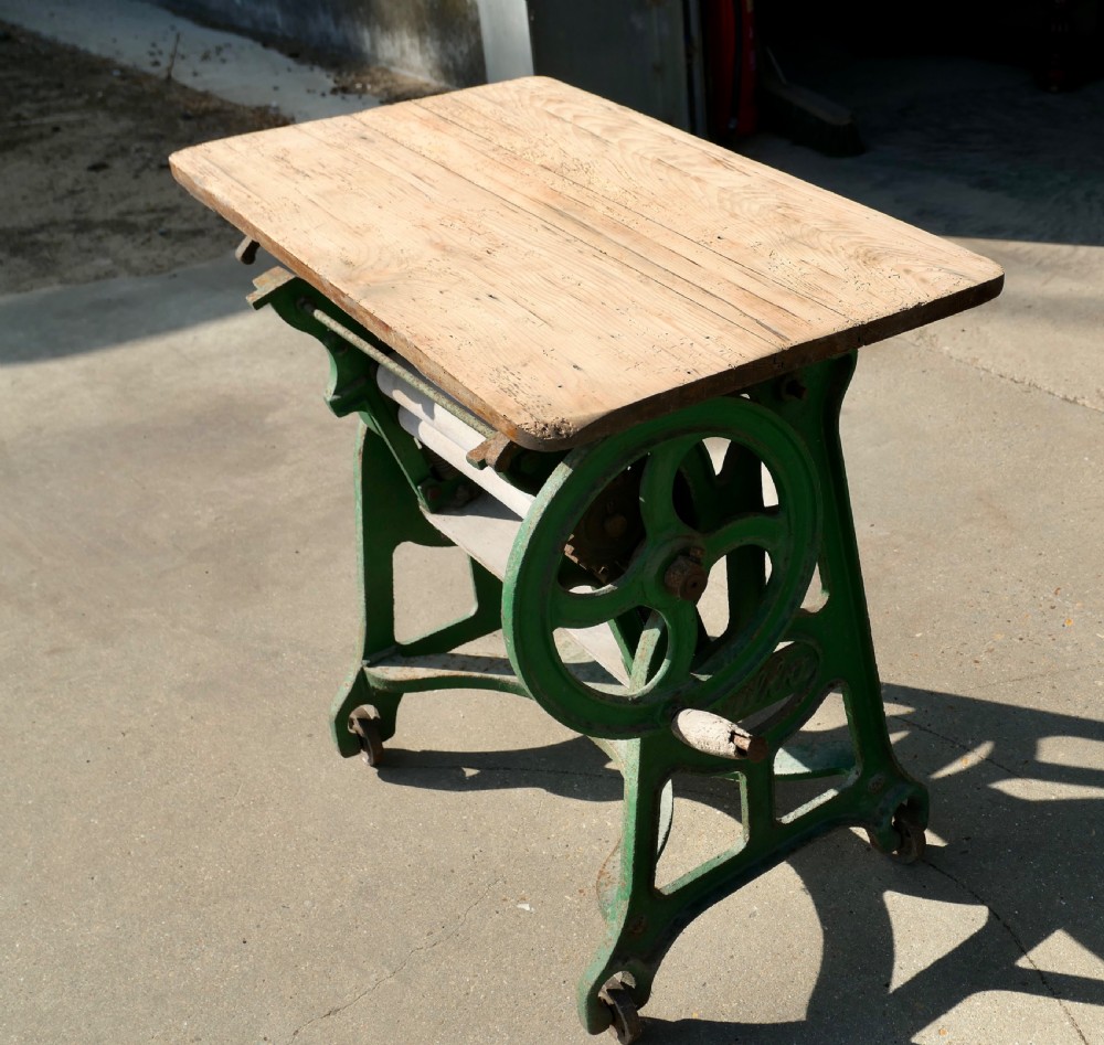 A green painted cast-iron mangle featuring an embossed Fulda logo, iron wheels, tension screws, and a hinged wooden pine top. View VI