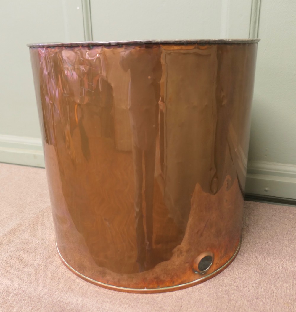 A cylindrical antique copper container featuring stamped numerical volume markings along a vertical seam. View II