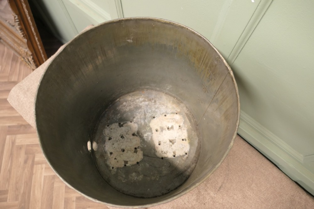 A cylindrical antique copper container featuring stamped numerical volume markings along a vertical seam. View VI