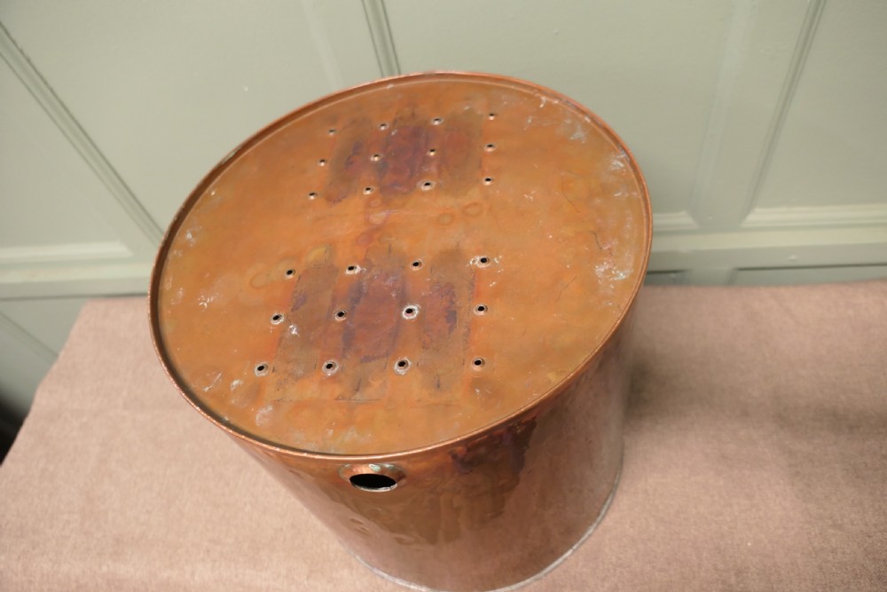 A cylindrical antique copper container featuring stamped numerical volume markings along a vertical seam. View VII