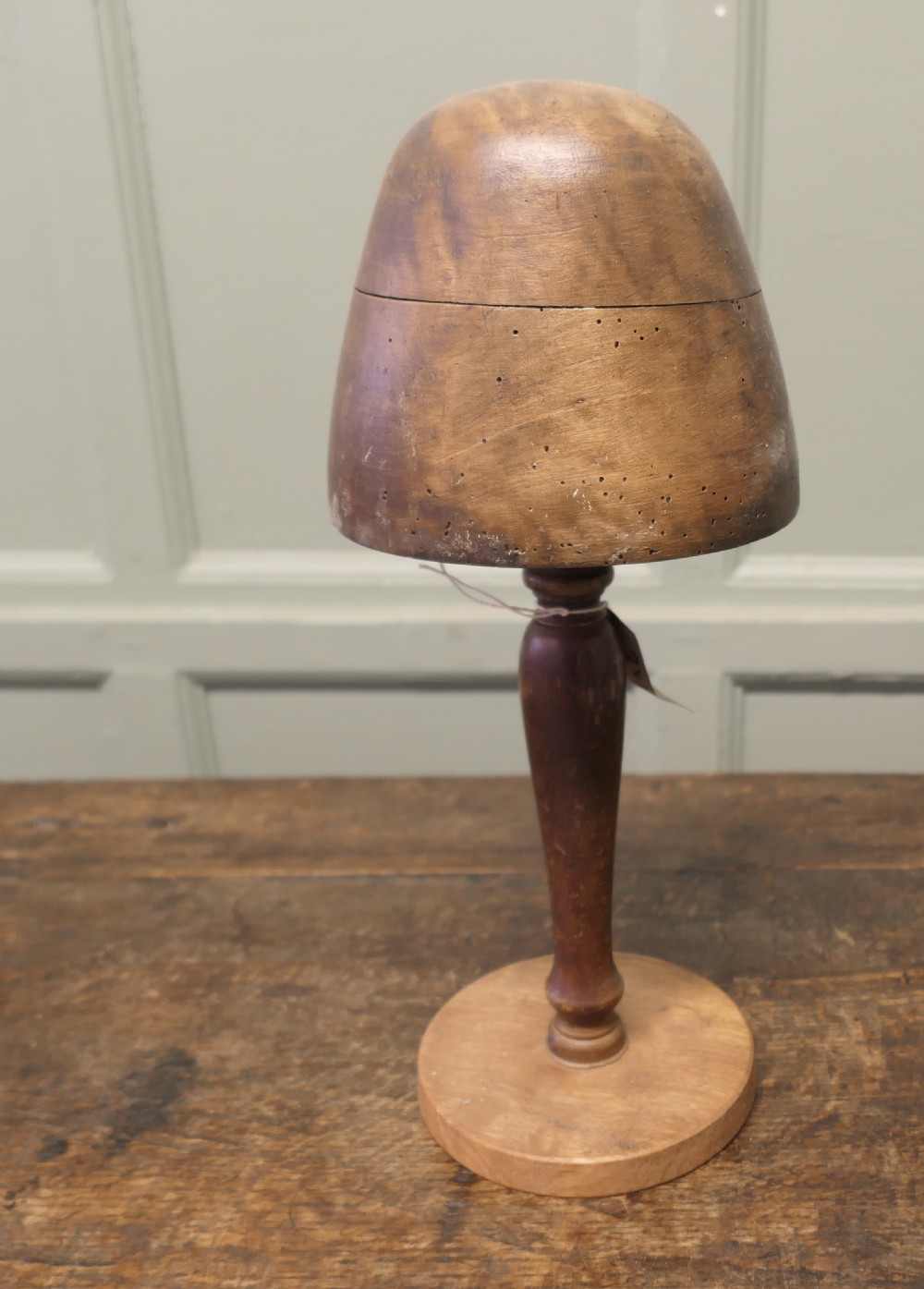 A turned wooden milliners hat form featuring a rounded dome crown mounted on a slender pedestal stem and circular base. View II