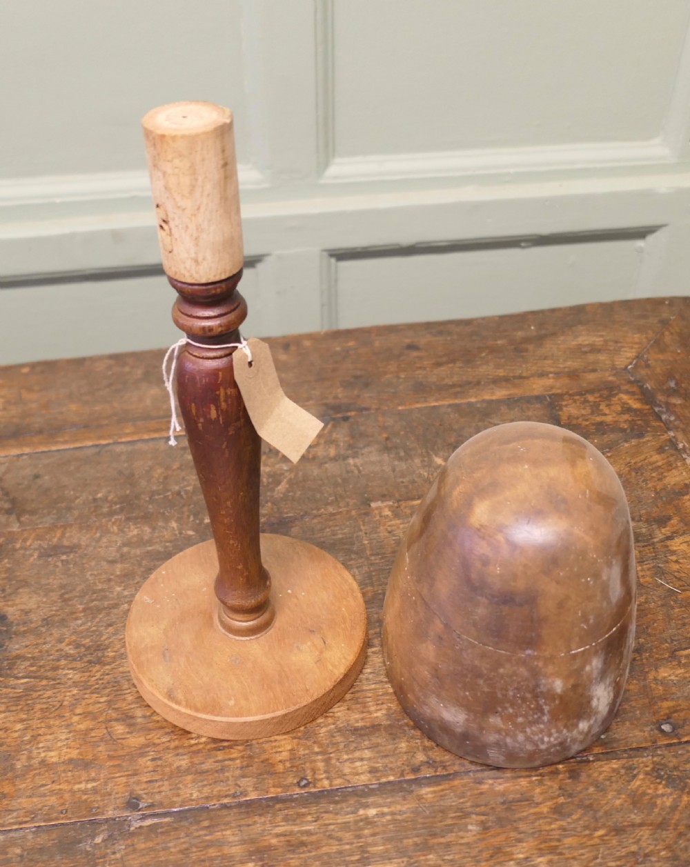 A turned wooden milliners hat form featuring a rounded dome crown mounted on a slender pedestal stem and circular base. View V