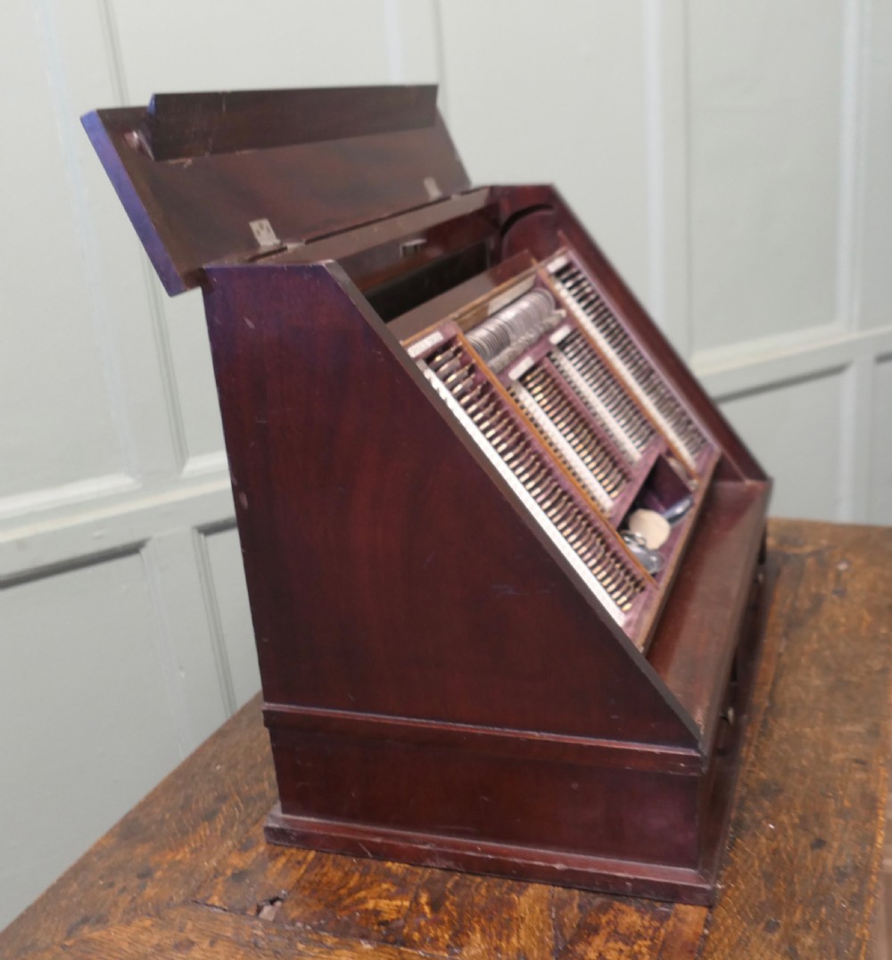 A nineteenth-century mahogany optician trial lens cabinet with a glass display door, brass fittings, and organized compartments containing optical test lenses. View V