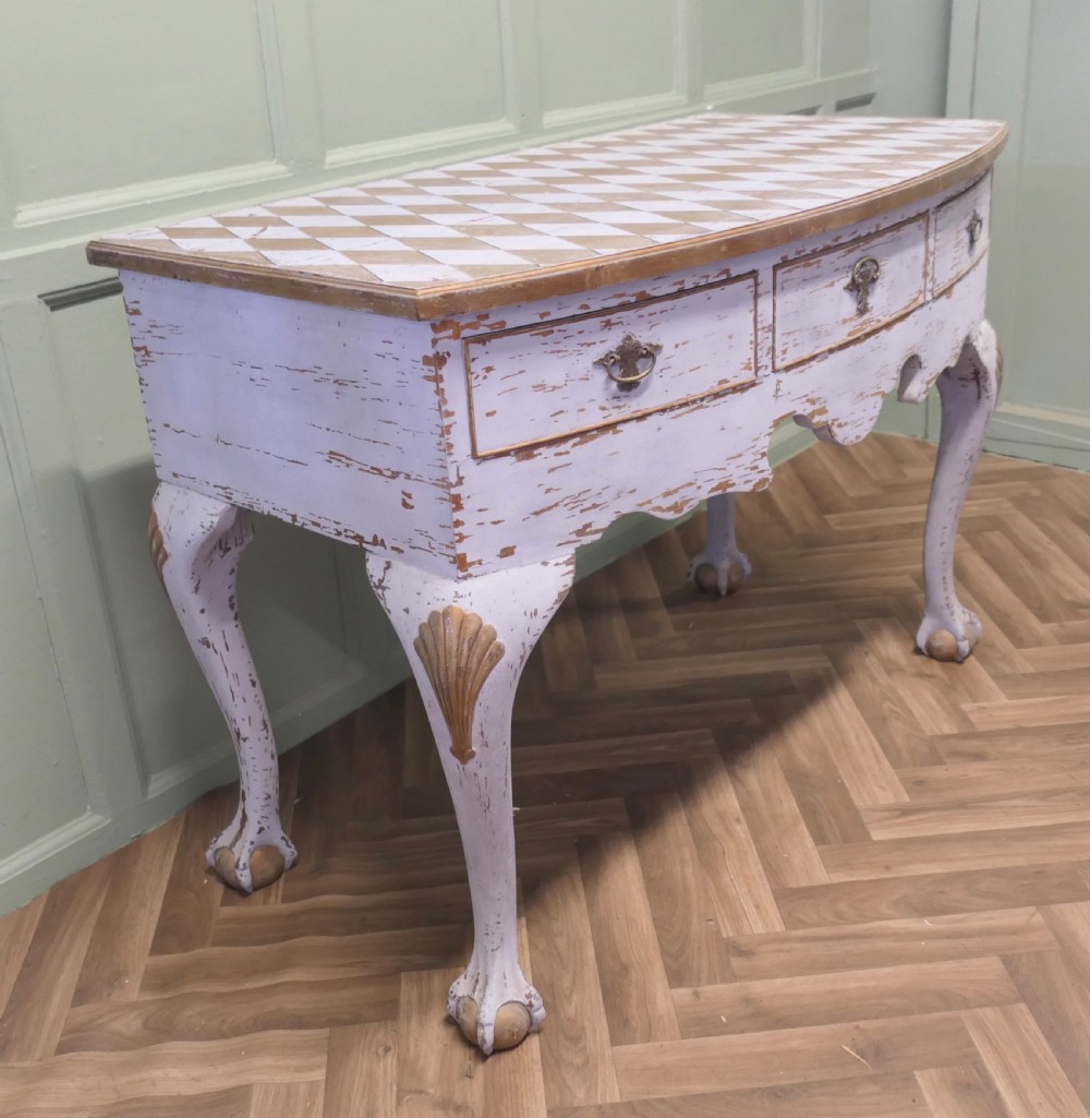 An eighteenth-century style painted bow-front console table featuring a diamond-pattern top, carved shell knees, claw-and-ball feet, and brass drawer handles.