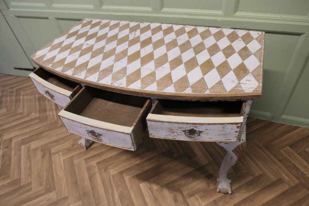 An eighteenth-century style painted bow-front console table featuring a diamond-pattern top, carved shell knees, claw-and-ball feet, and brass drawer handles. View V