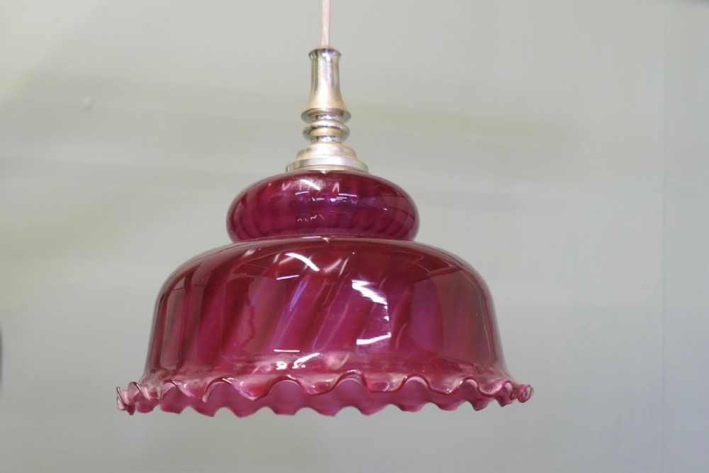 A Victorian ruby red glass pendant lampshade featuring a tiered dome shape, spiral swirled texture, ruffled lower edge, and a silver-toned metal gallery fitting. View III