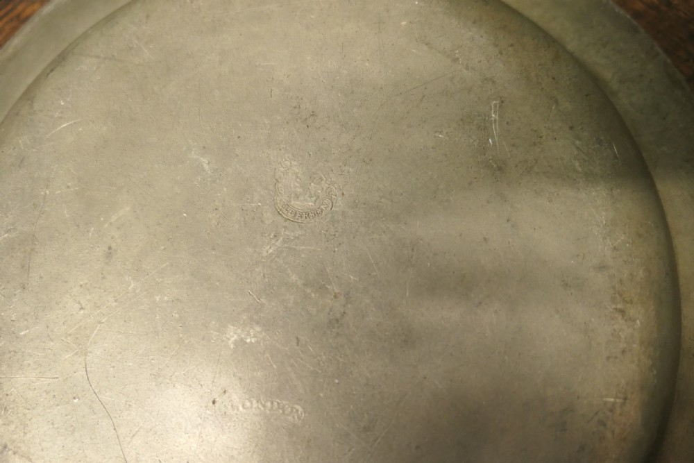A pair of large round antique pewter charger plates with stamped initials on the rims. View II