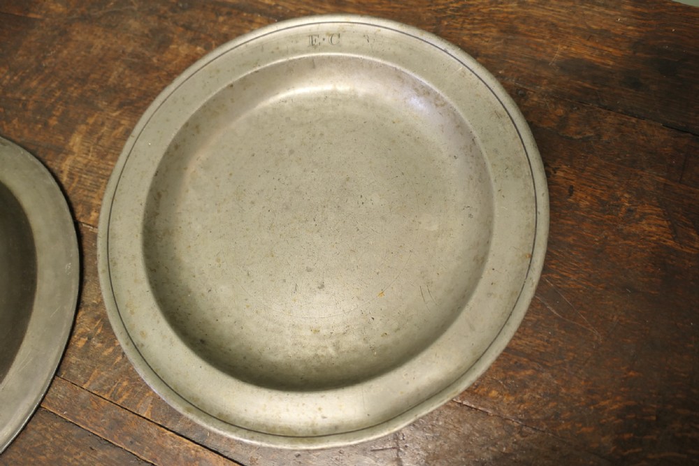 A pair of large round antique pewter charger plates with stamped initials on the rims. View III