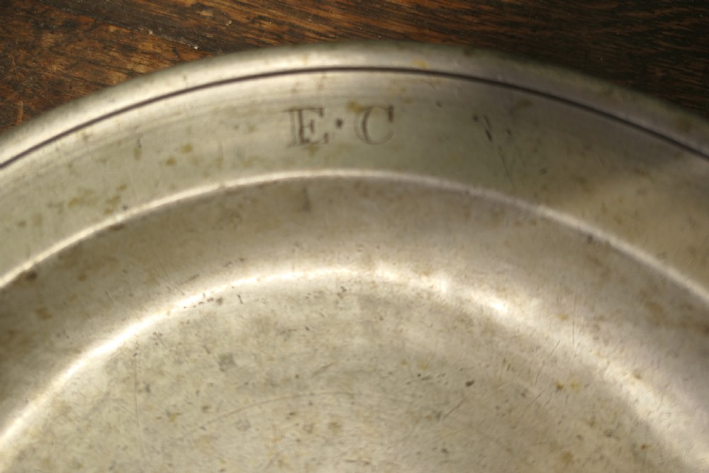 A pair of large round antique pewter charger plates with stamped initials on the rims. View VI