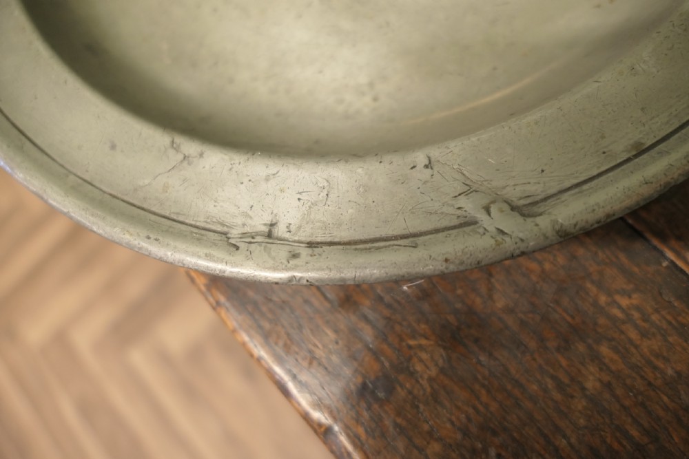 A pair of large round antique pewter charger plates with stamped initials on the rims. View VII