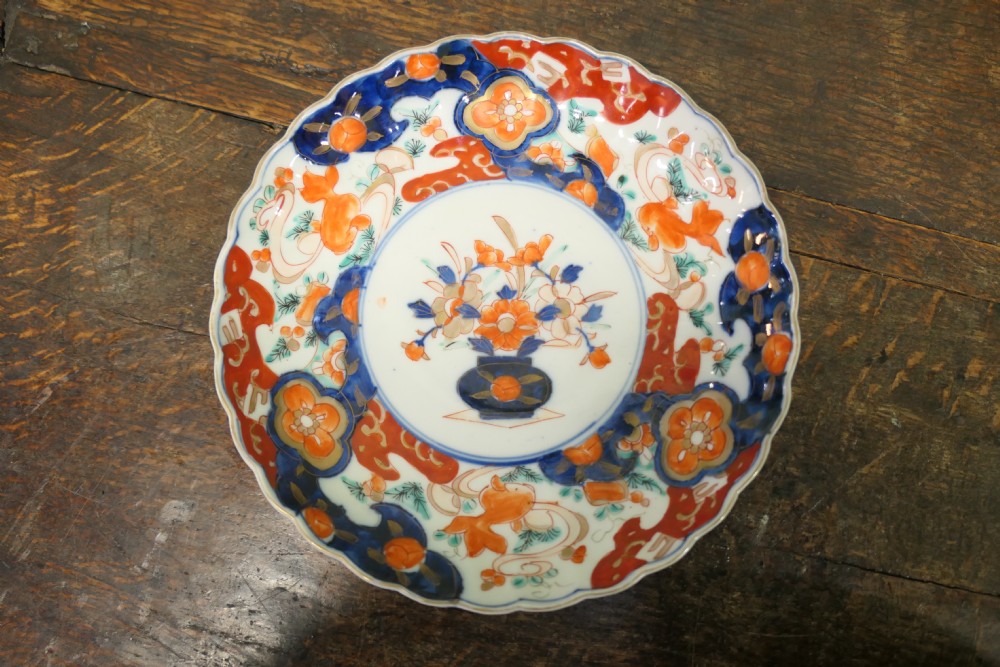 A set of three 19th-century Imari ironstone ceramic plates featuring scalloped edges and hand-painted blue, terracotta, and white floral motifs. View II