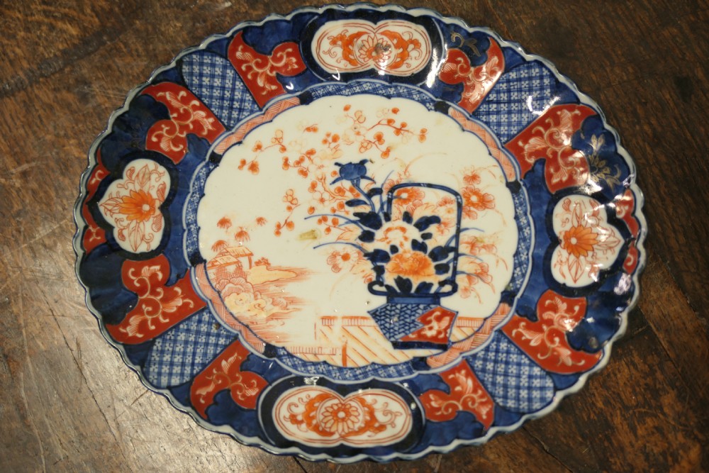 A set of three 19th-century Imari ironstone ceramic plates featuring scalloped edges and hand-painted blue, terracotta, and white floral motifs. View V