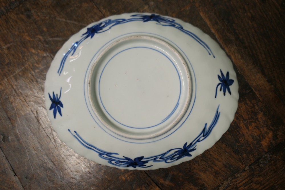 A set of three 19th-century Imari ironstone ceramic plates featuring scalloped edges and hand-painted blue, terracotta, and white floral motifs. View VI