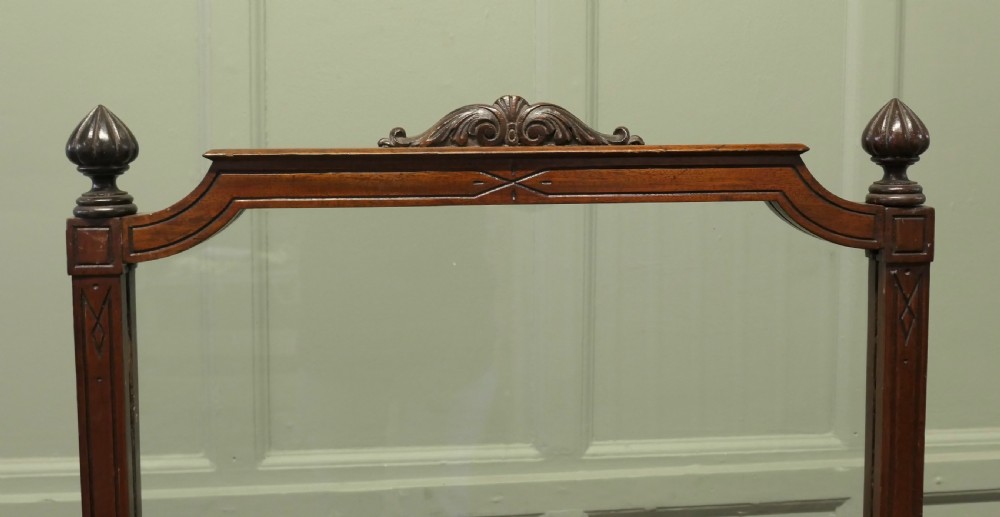A freestanding Victorian dark mahogany fire screen featuring a clear glass panel, carved finials, turned side columns, and splayed trestle feet. View III