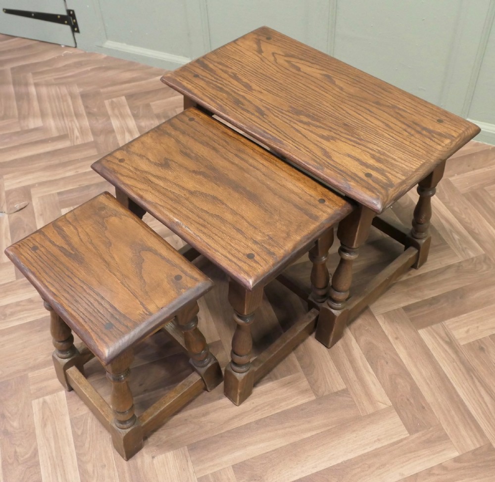 A set of three dark oak nesting side tables in graduated sizes featuring turned baluster legs and base stretchers. View III