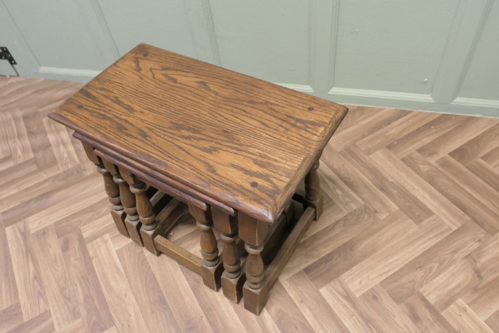 A set of three dark oak nesting side tables in graduated sizes featuring turned baluster legs and base stretchers. View V