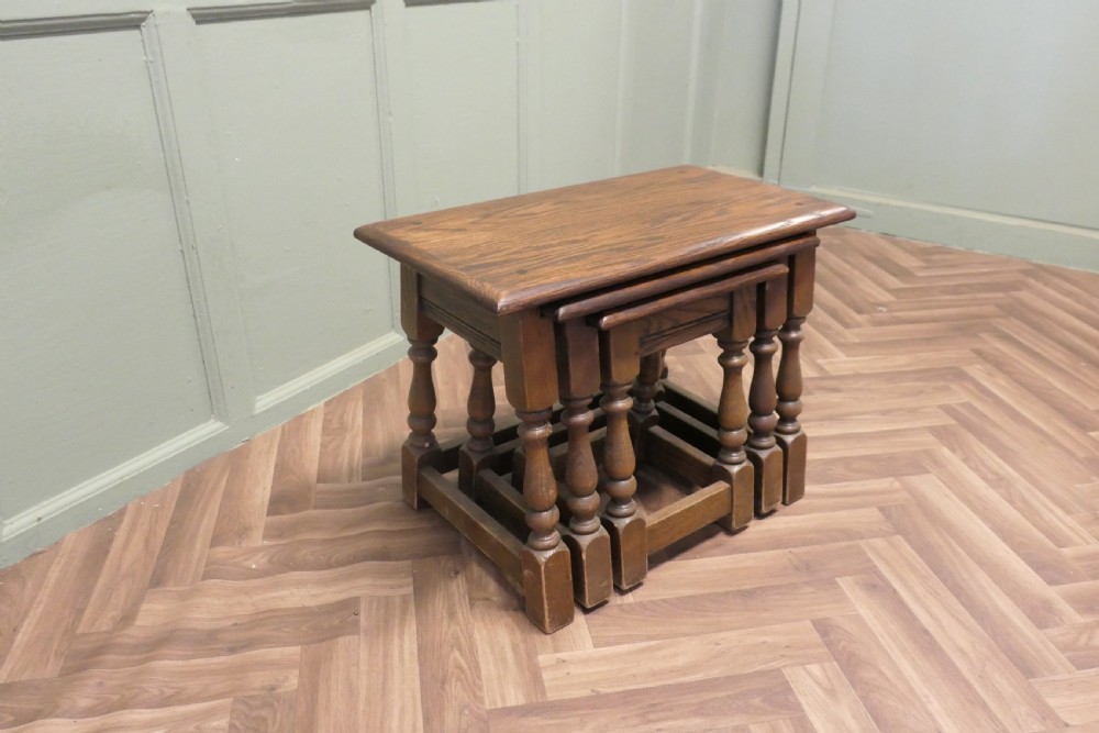 A set of three dark oak nesting side tables in graduated sizes featuring turned baluster legs and base stretchers. View VII